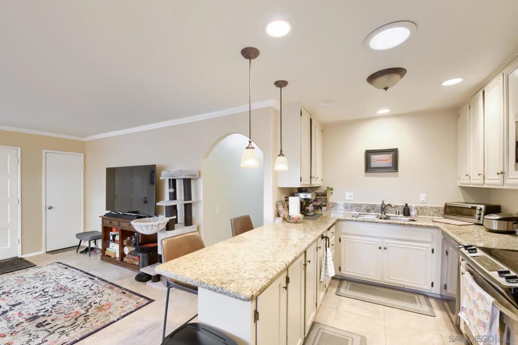 View across the great room showing the curved archway between the kitchen and hallway, granite peninsula, and white cabinetry